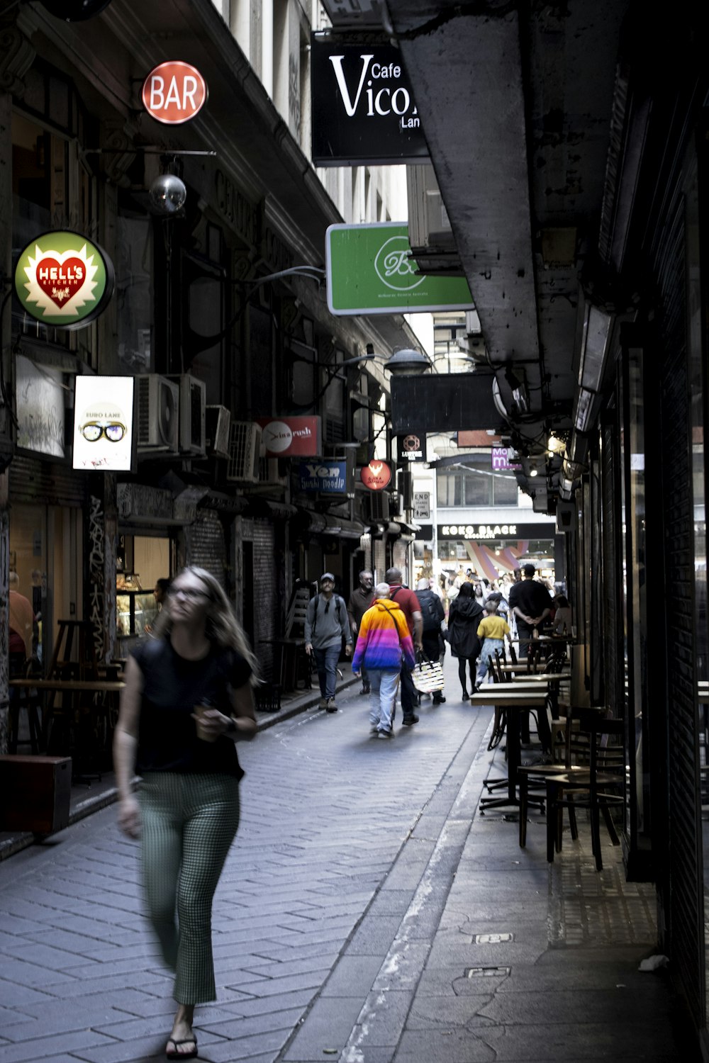 a woman walking down a street next to tall buildings