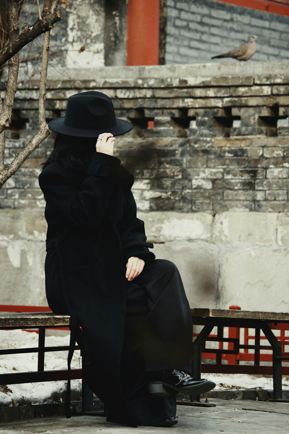 a woman sitting on a bench wearing a black hat