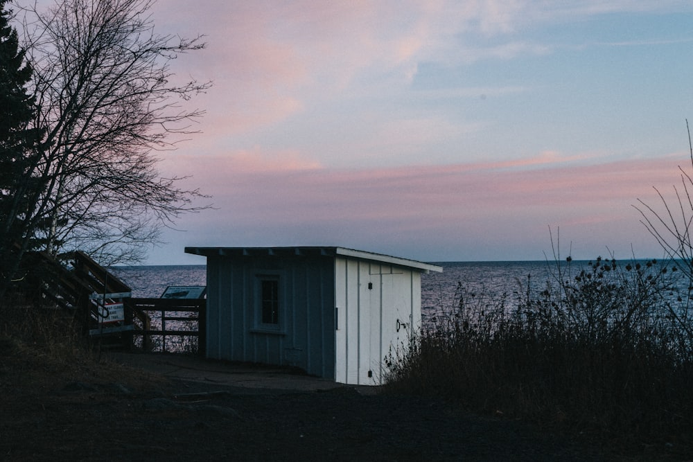 a small outhouse sitting next to a body of water