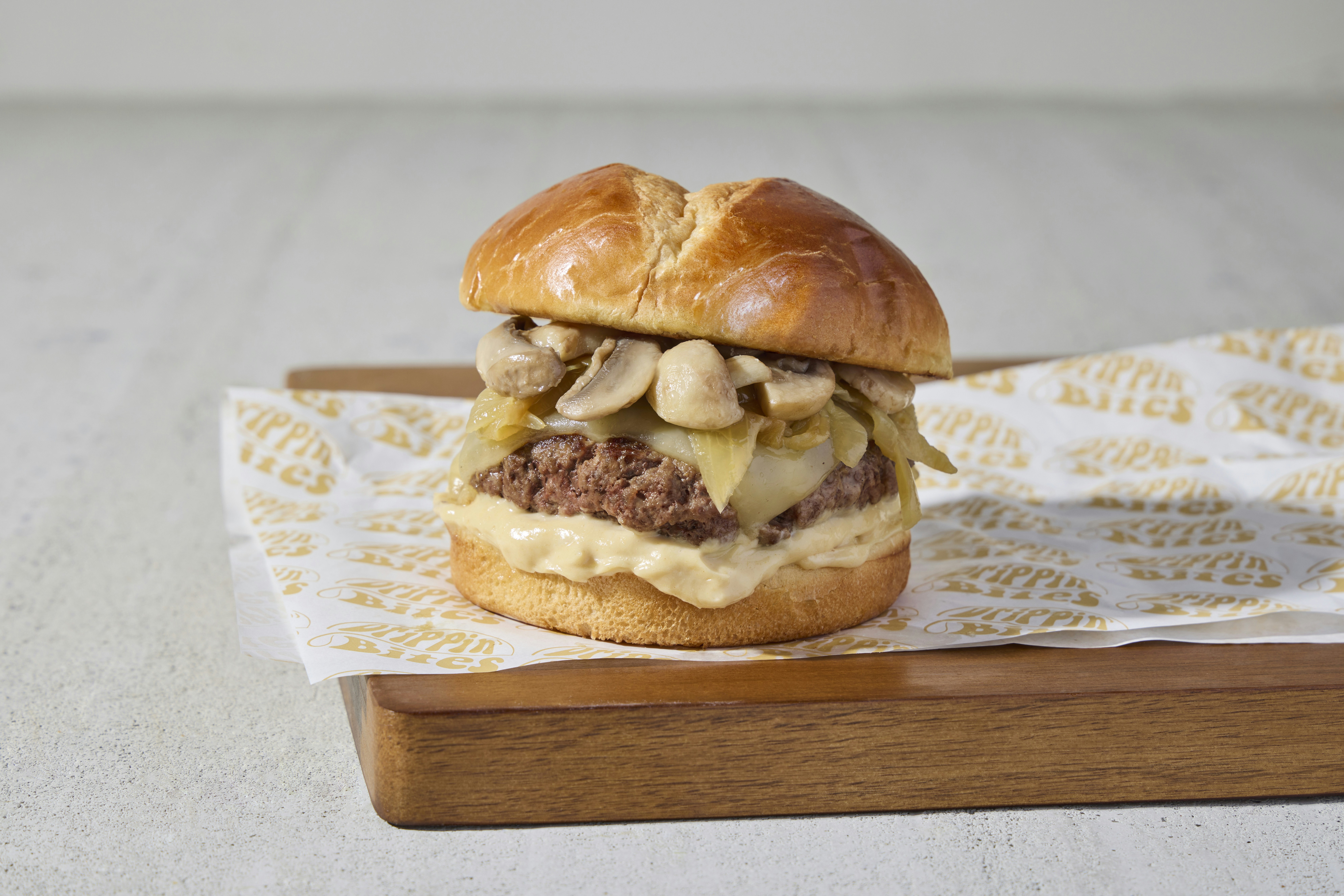 a hamburger with mushrooms on a wooden tray