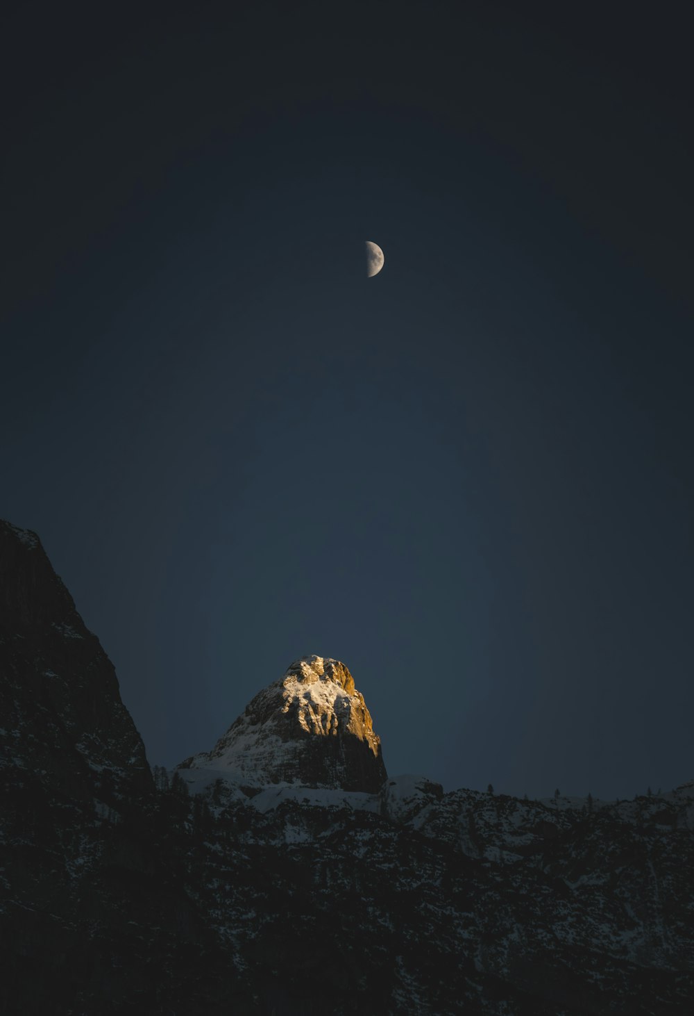 the moon is setting over a snowy mountain