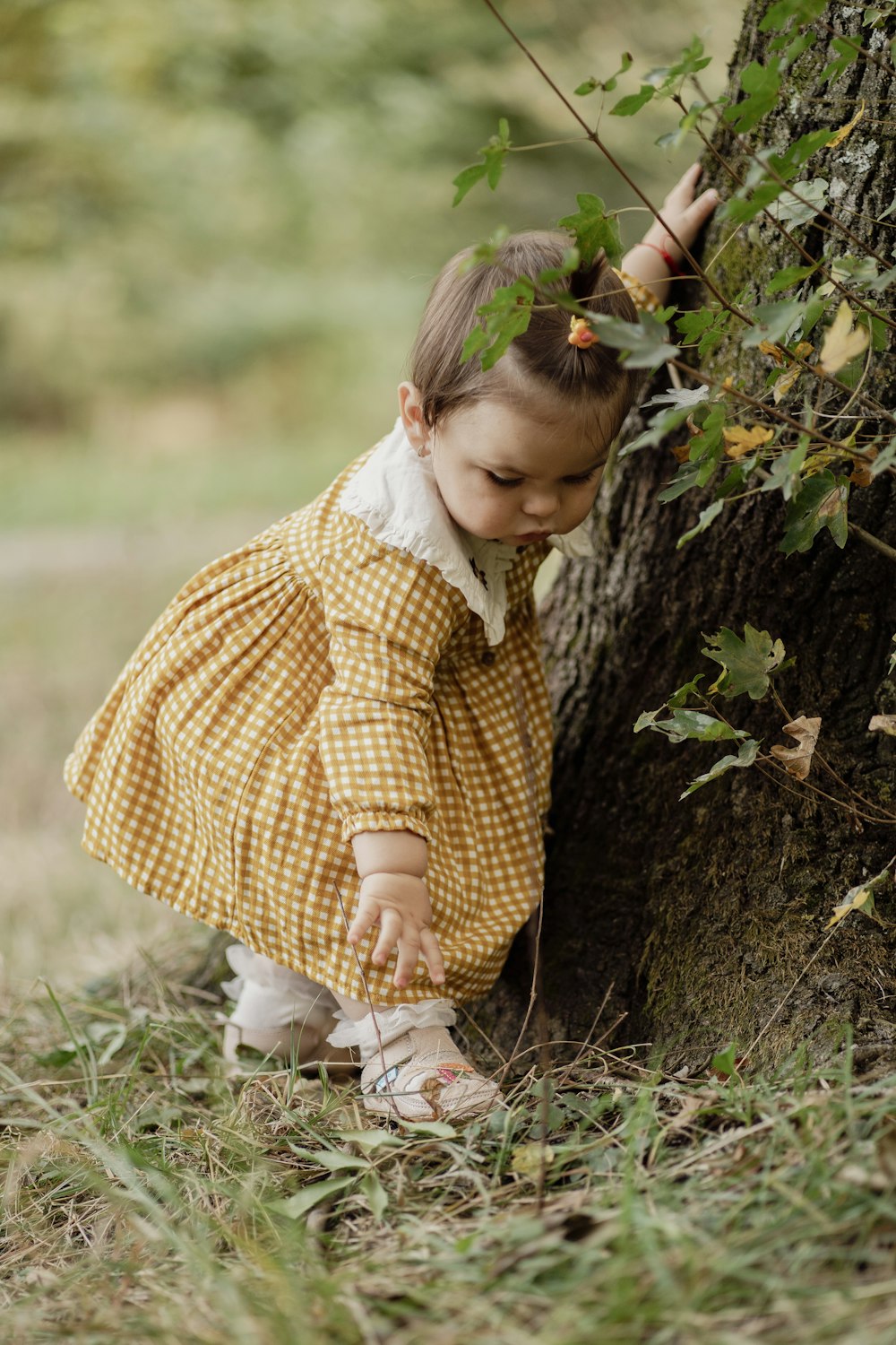 a little girl standing next to a tree