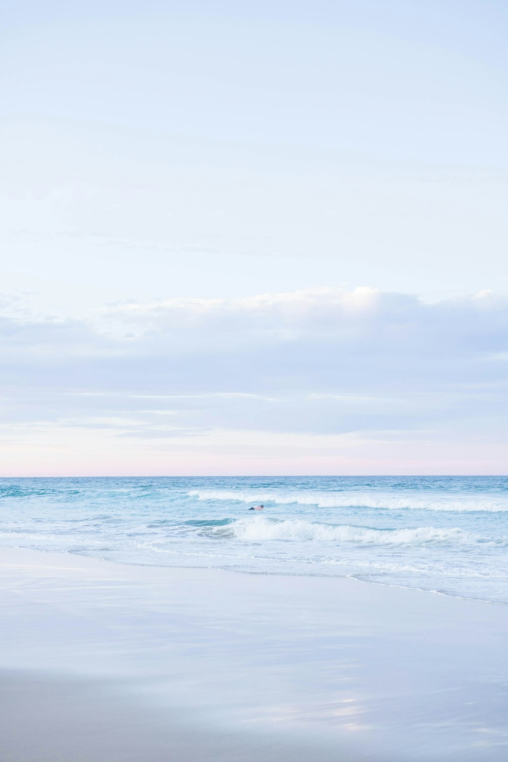 a person walking on the beach carrying a surfboard