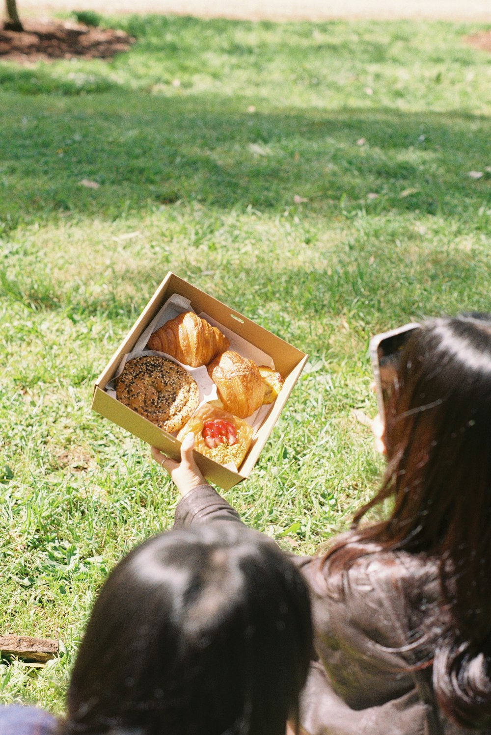 a person holding a box of food in the grass