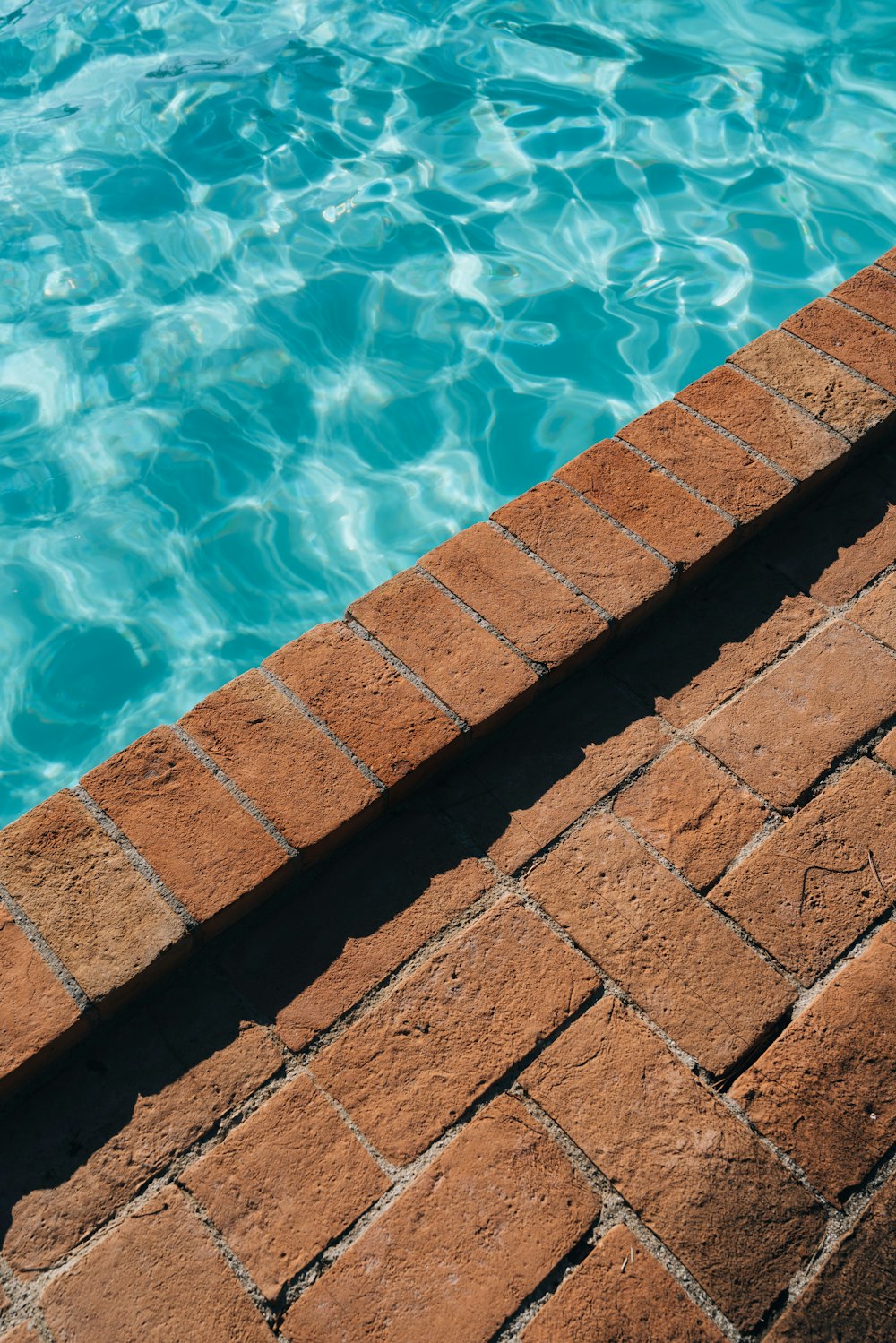 a brick wall next to a swimming pool