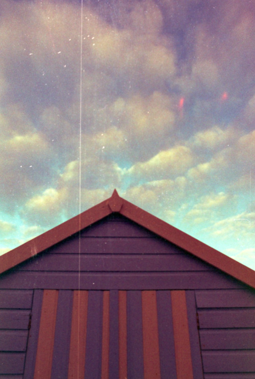 a purple building with a red roof under a cloudy sky