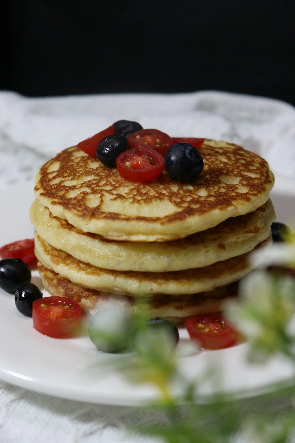 a stack of pancakes topped with berries and syrup