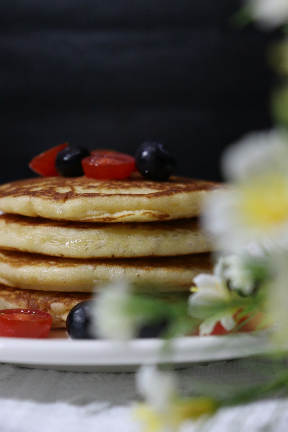 a stack of pancakes with blueberries and tomatoes on a plate