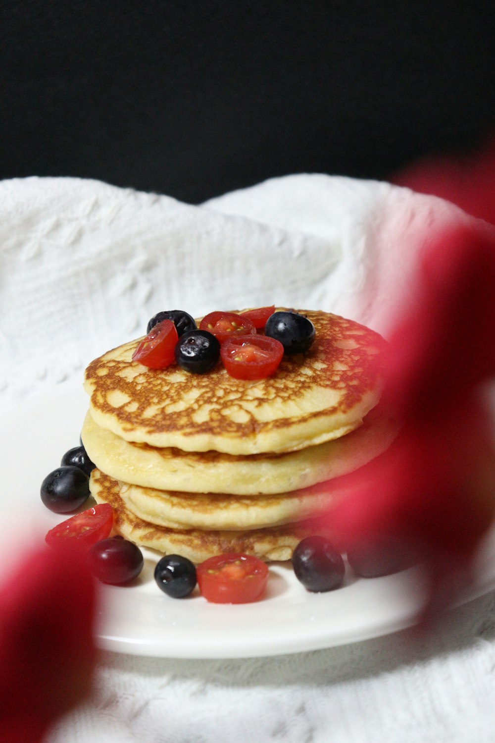 a stack of pancakes topped with berries and syrup