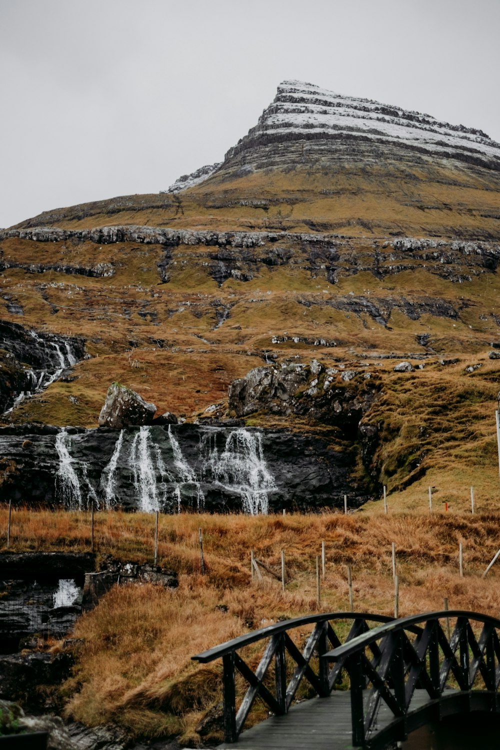 a bridge crosses a stream in front of a mountain