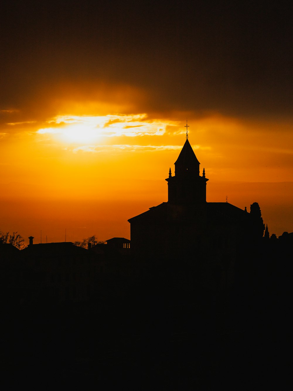 the sun is setting behind a building with a steeple