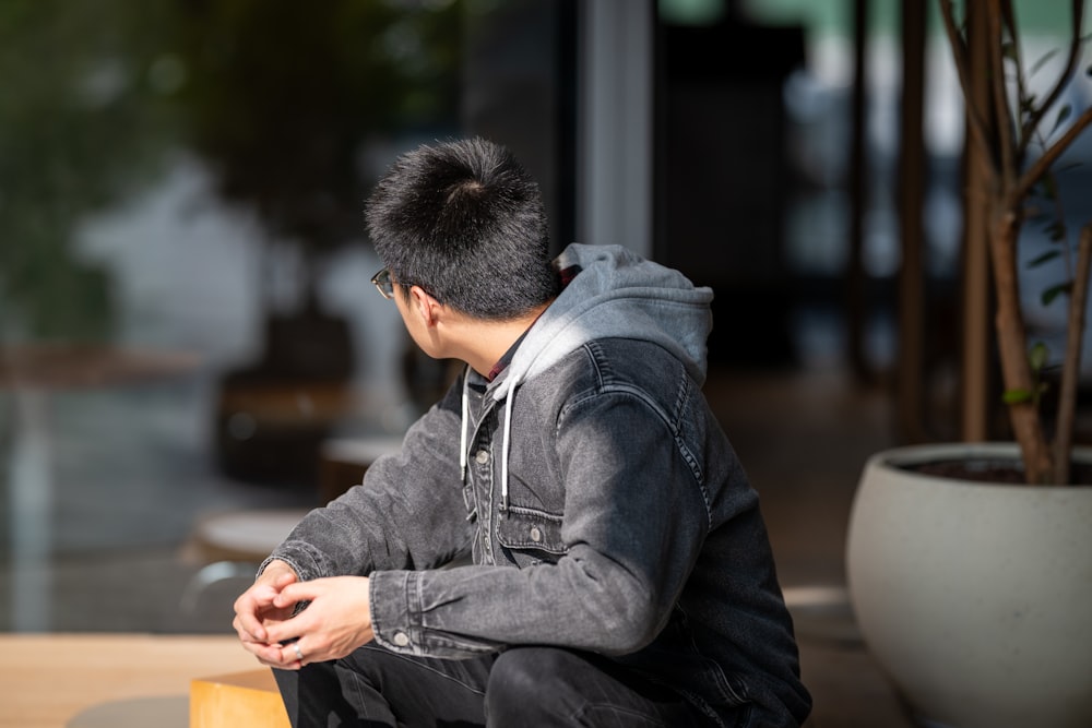 a man sitting on a table with his hands in his pockets