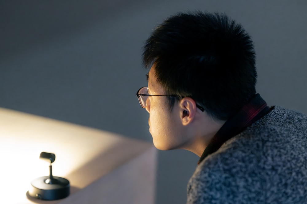 a man with glasses looking at a light