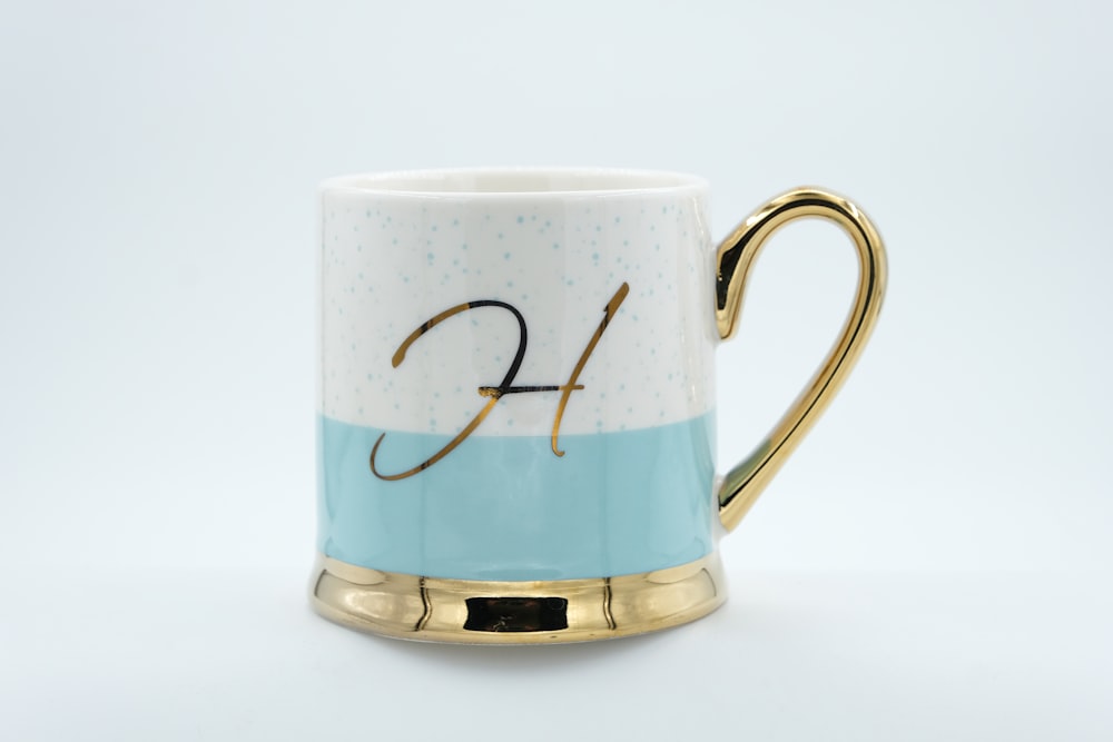 a blue and white coffee mug with a gold handle