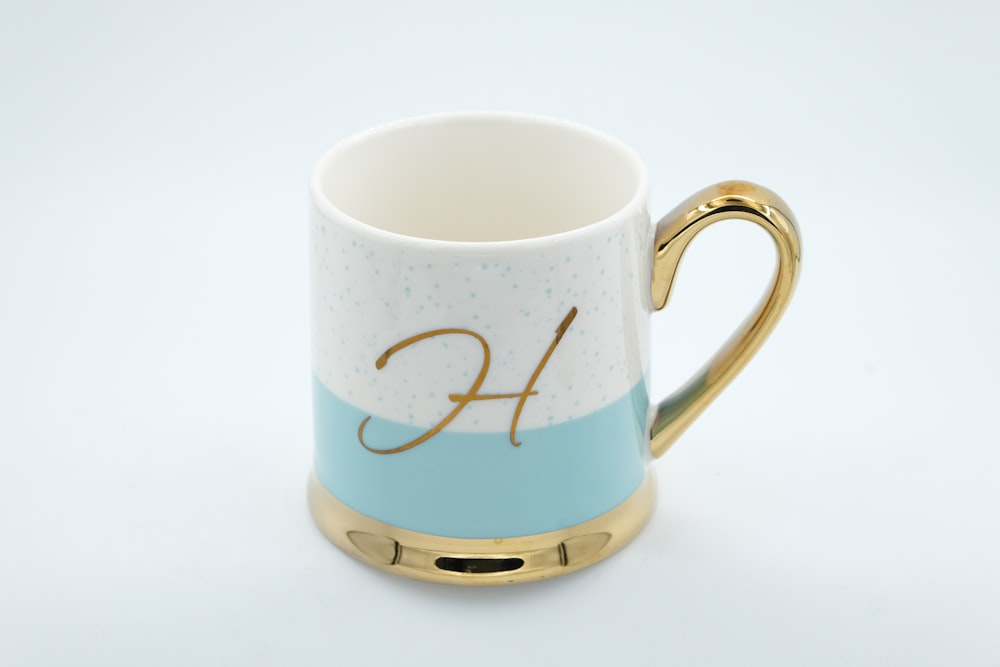 a blue and white coffee mug with a gold handle