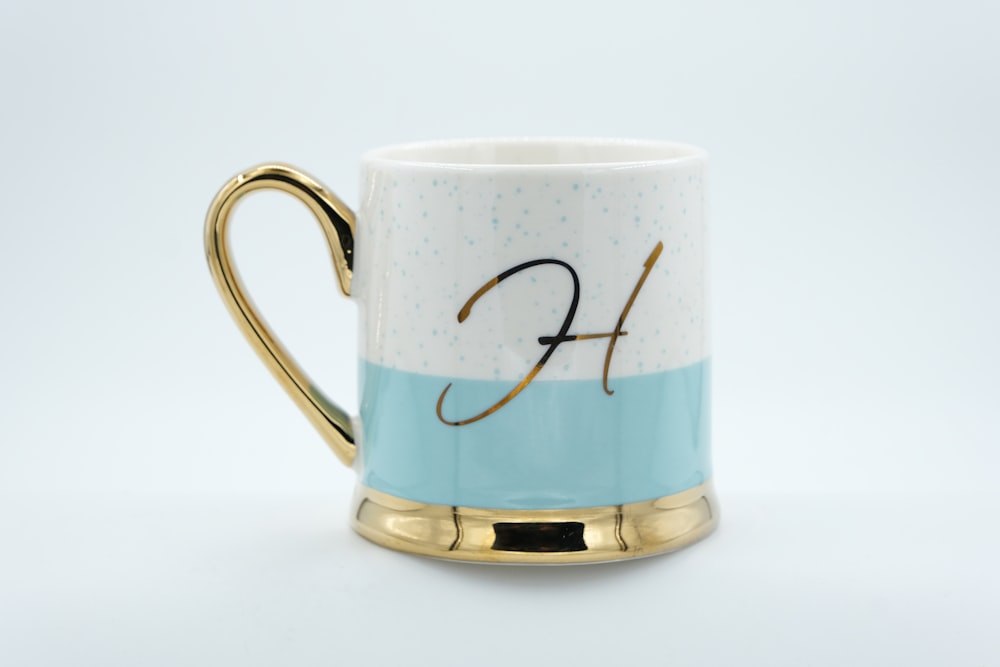 a blue and white coffee mug with a gold handle