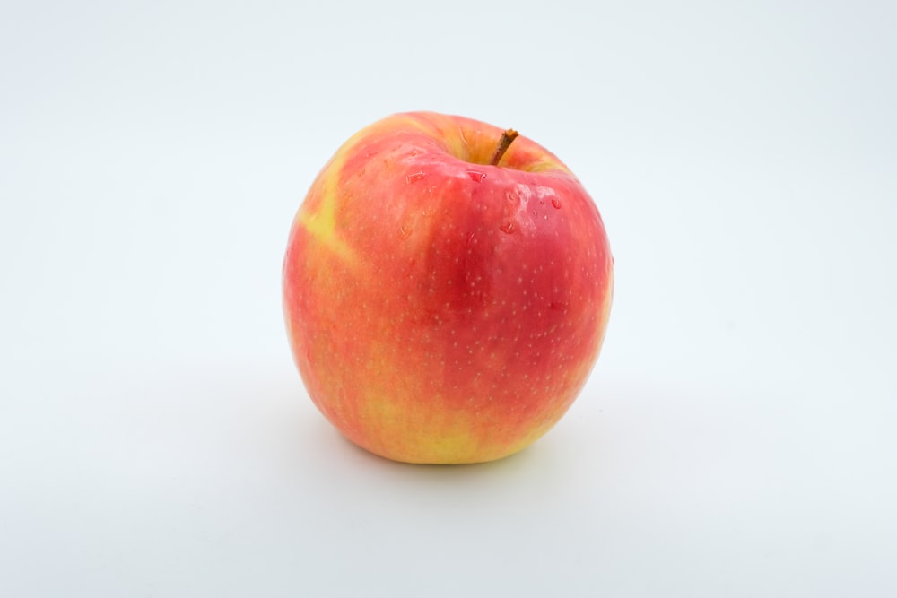 a red apple sitting on top of a white table