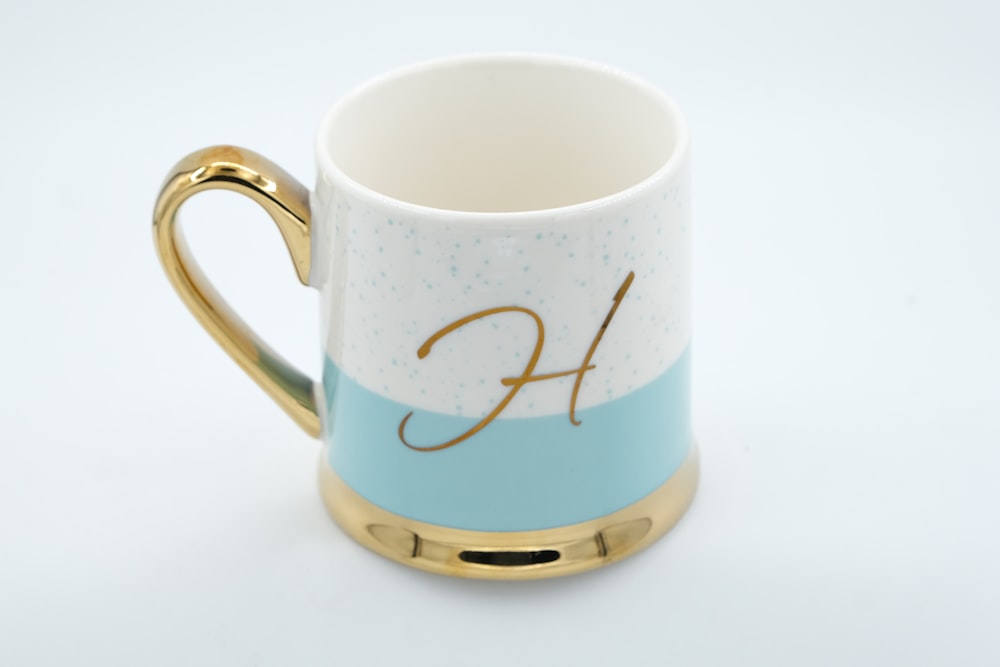 a blue and white coffee mug with a gold handle