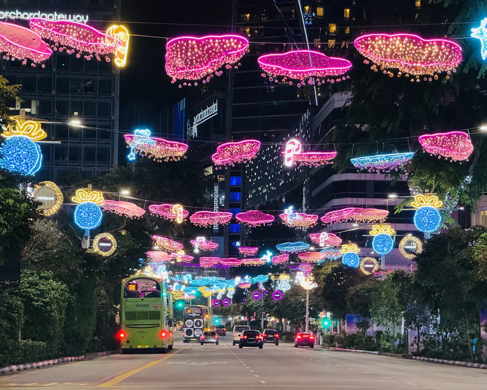 A city street at night strung with elaborate Christmas lights and illuminated decorations