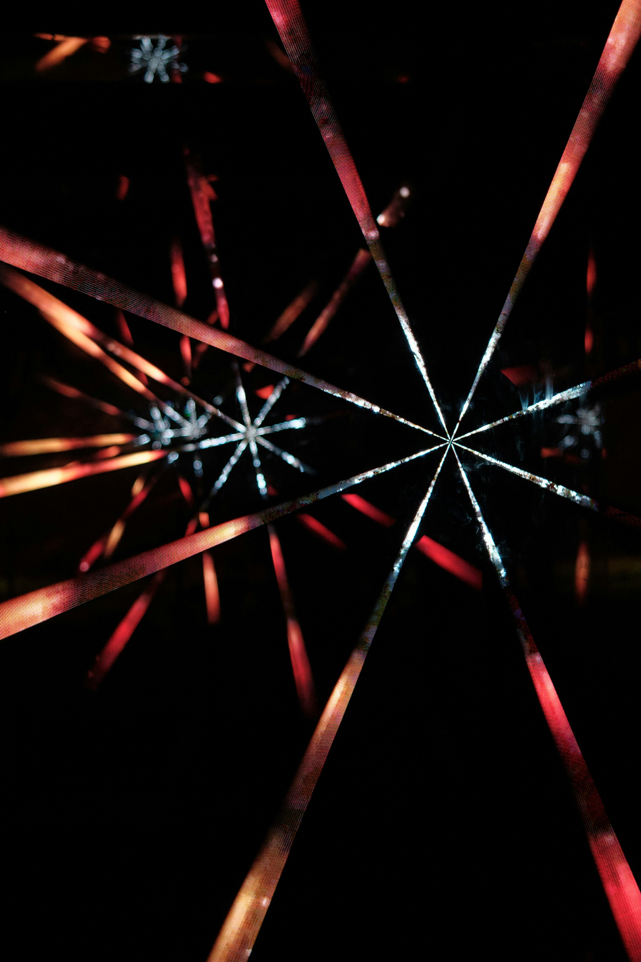 Glowing digital light beams form intersecting starburst patterns.