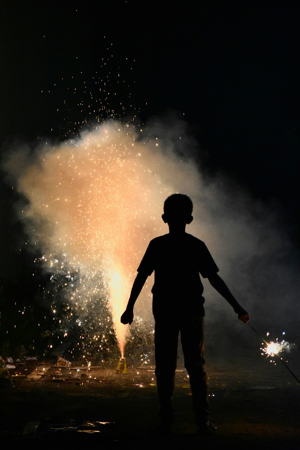 un uomo in piedi davanti a un fuoco d'artificio di notte