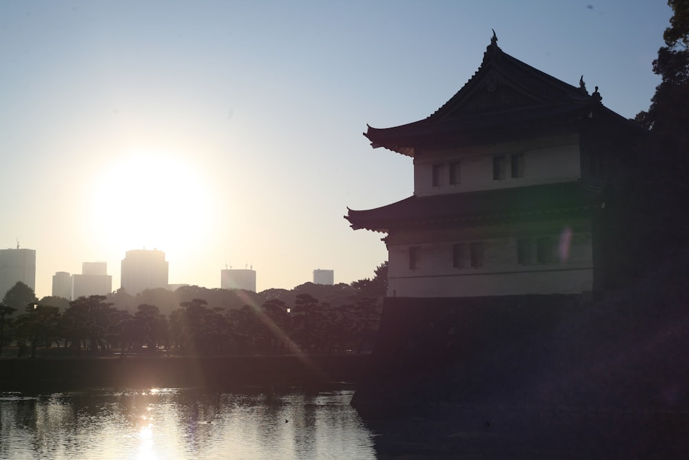 Die Sonne geht hinter einem Gebäude am Wasser unter