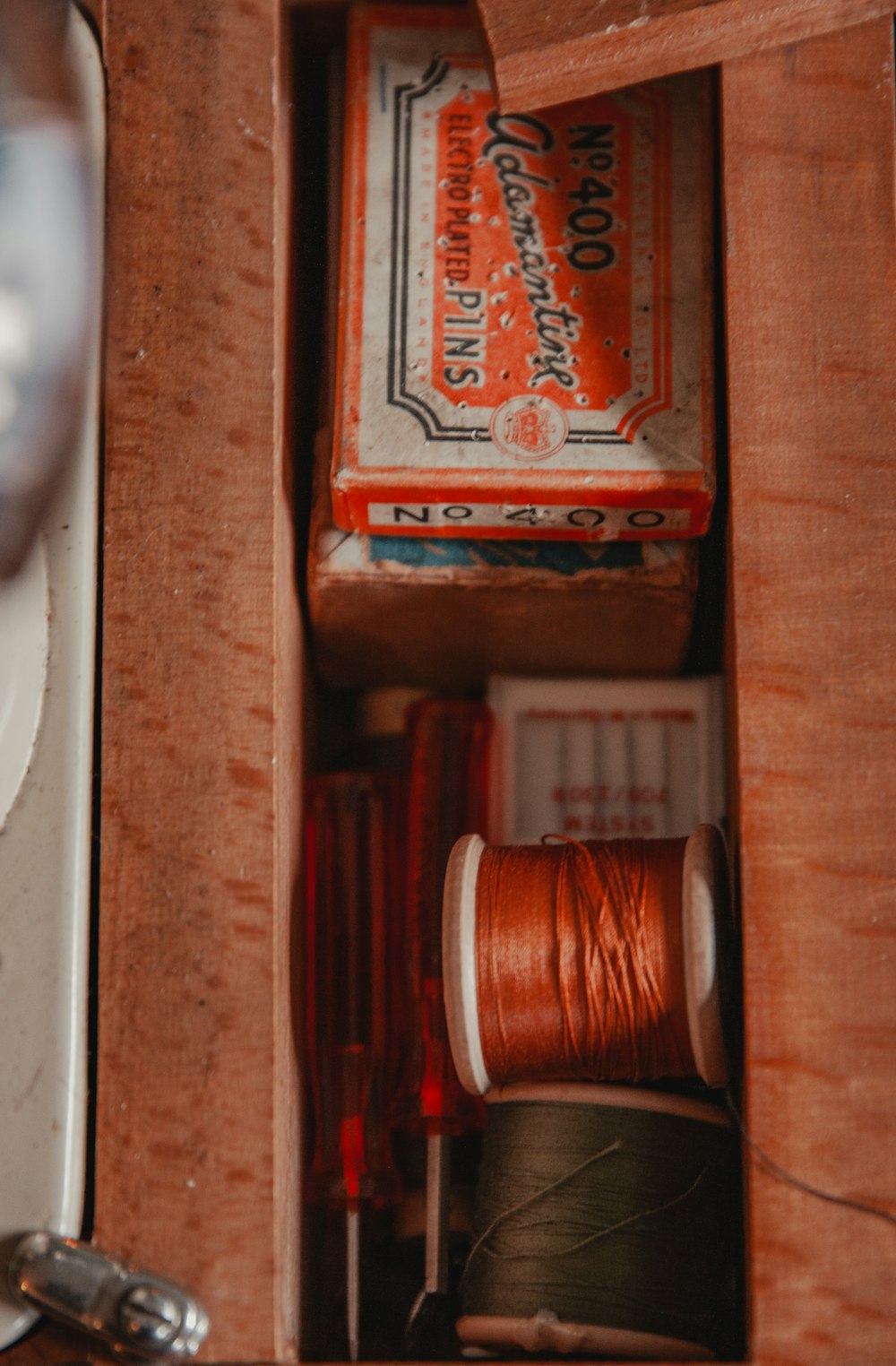 a wooden box with a spool of thread inside of it