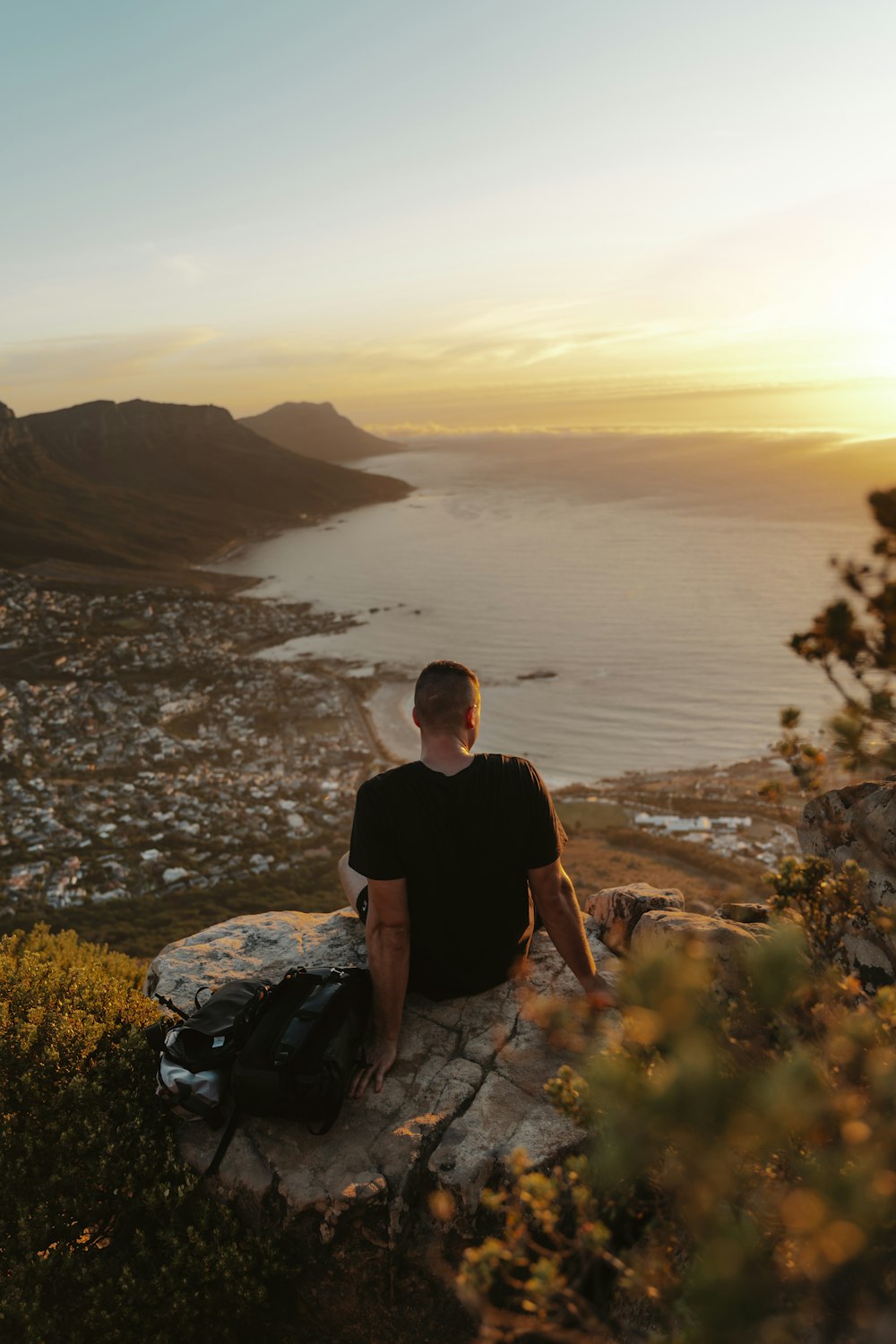 a man sitting on top of a rock next to a body of water