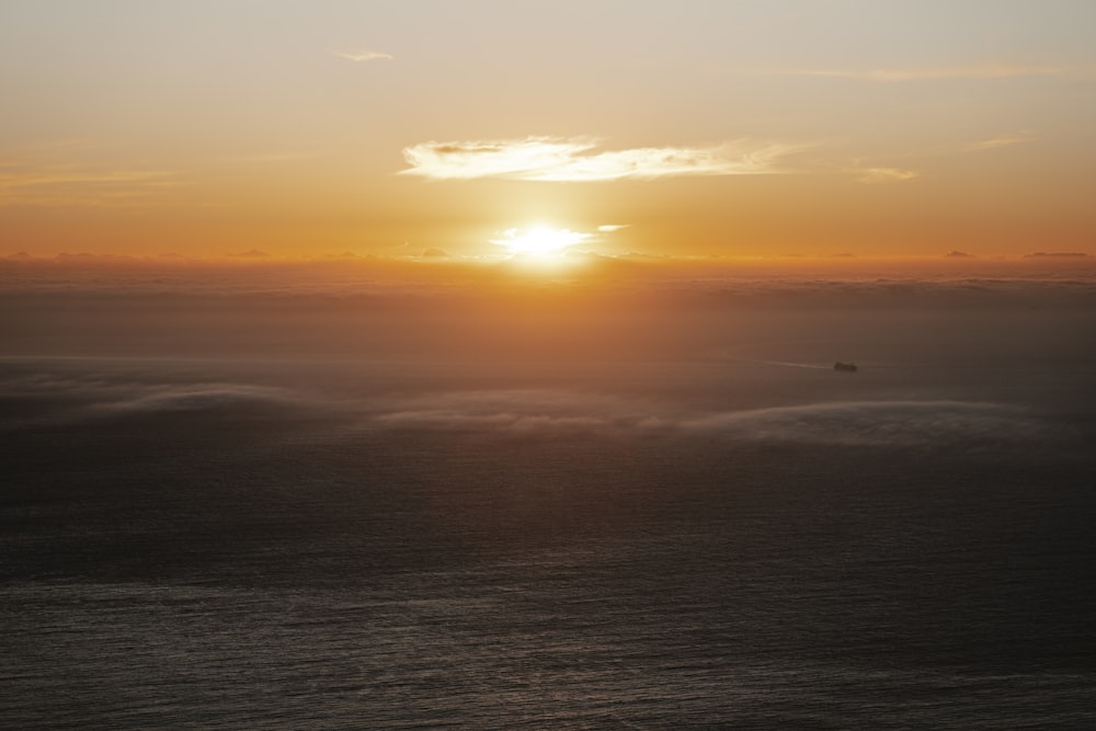 the sun is setting over the ocean on a foggy day