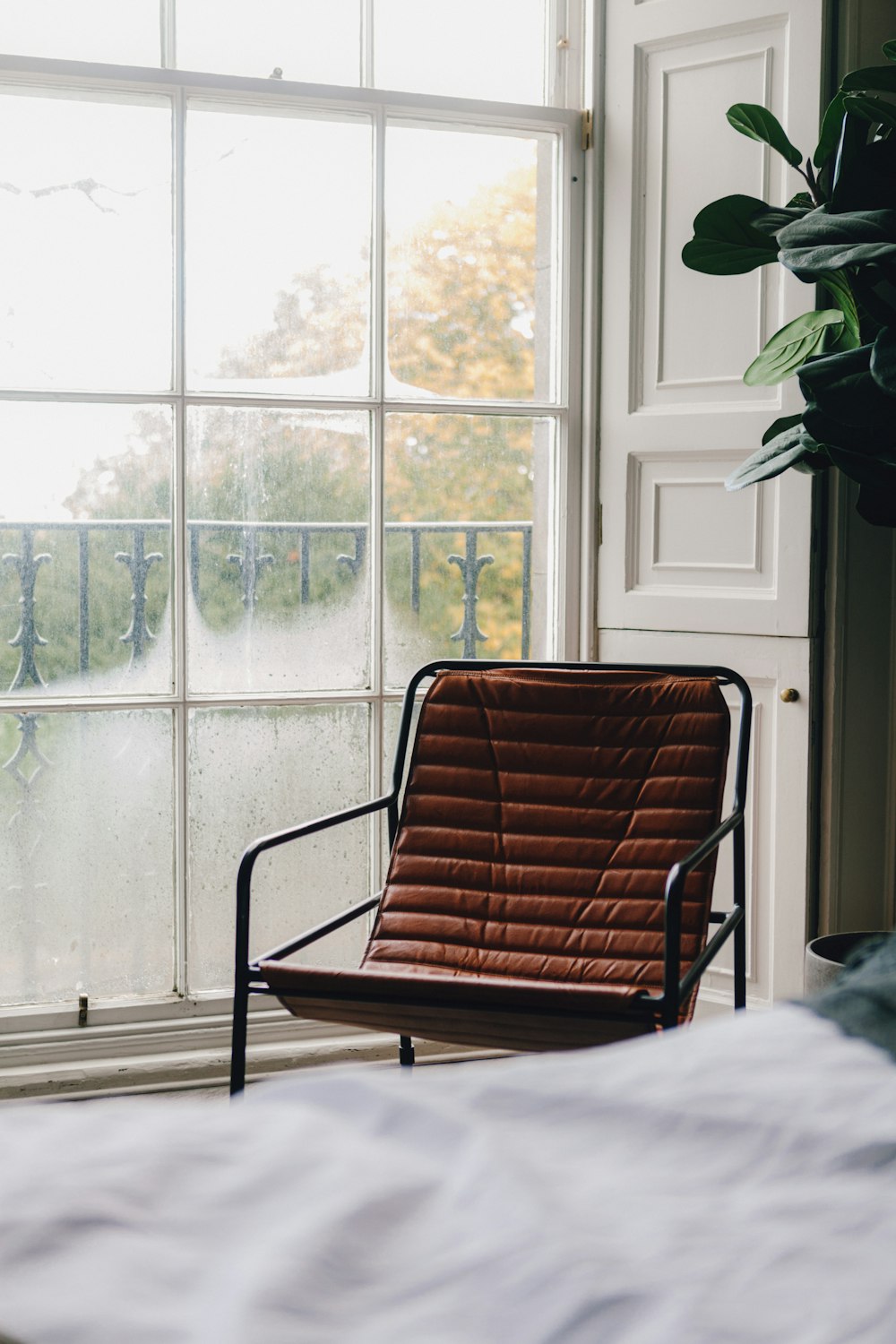 a chair sitting in front of a window next to a plant