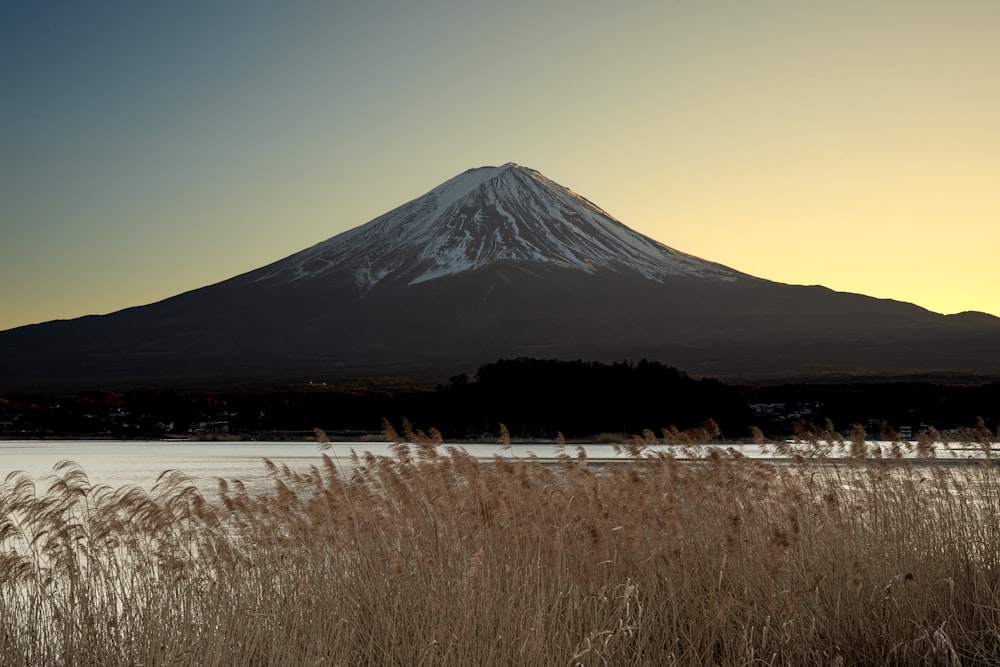 a snow covered mountain in the distance with a lake in the foreground