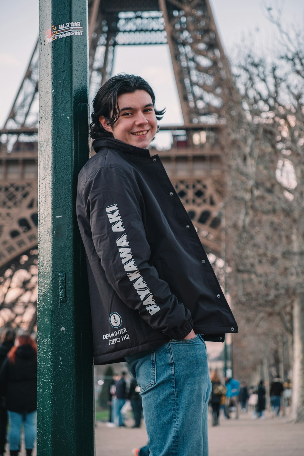 a man standing next to a green pole near the eiffel tower