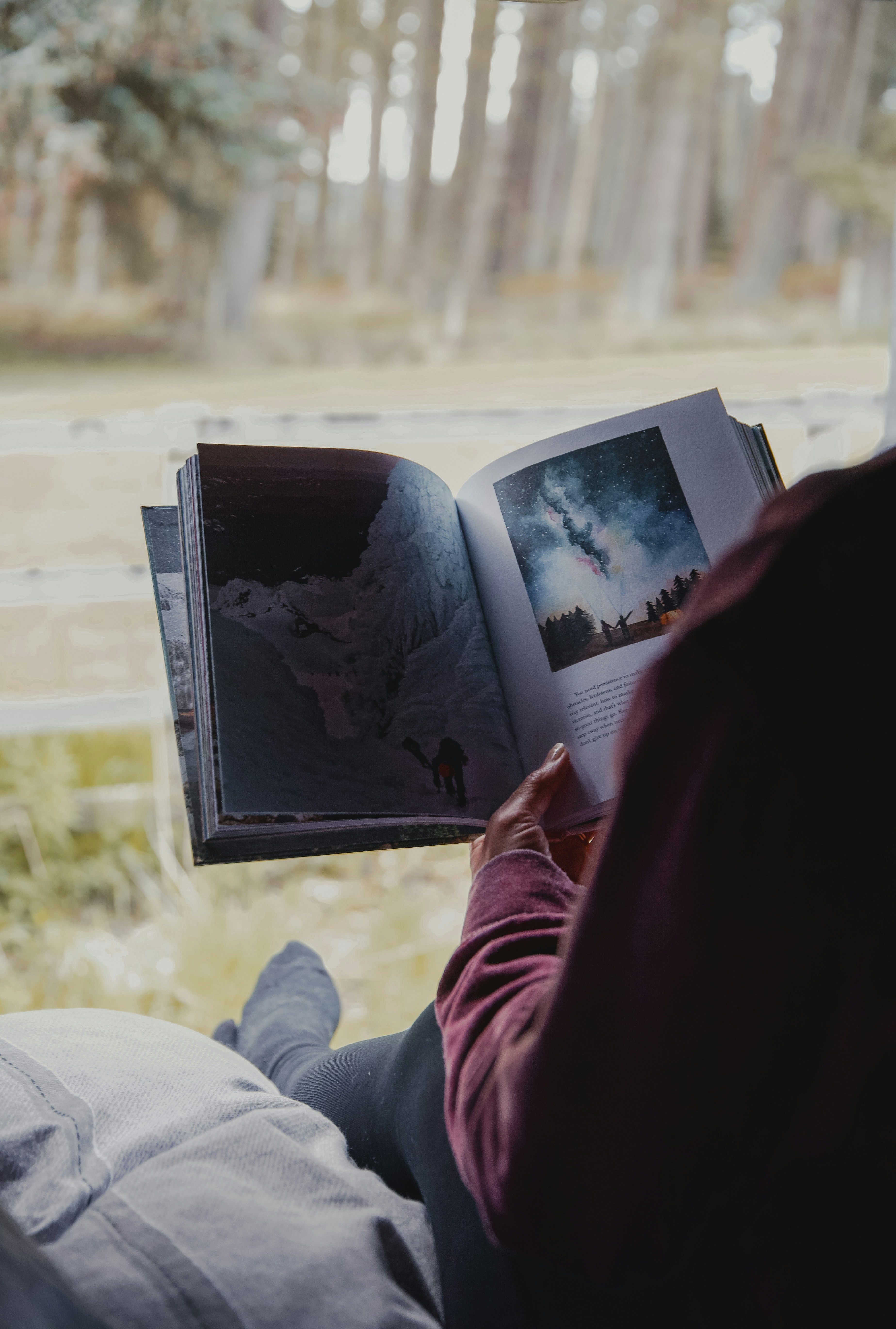 a person reading a book while sitting in a chair