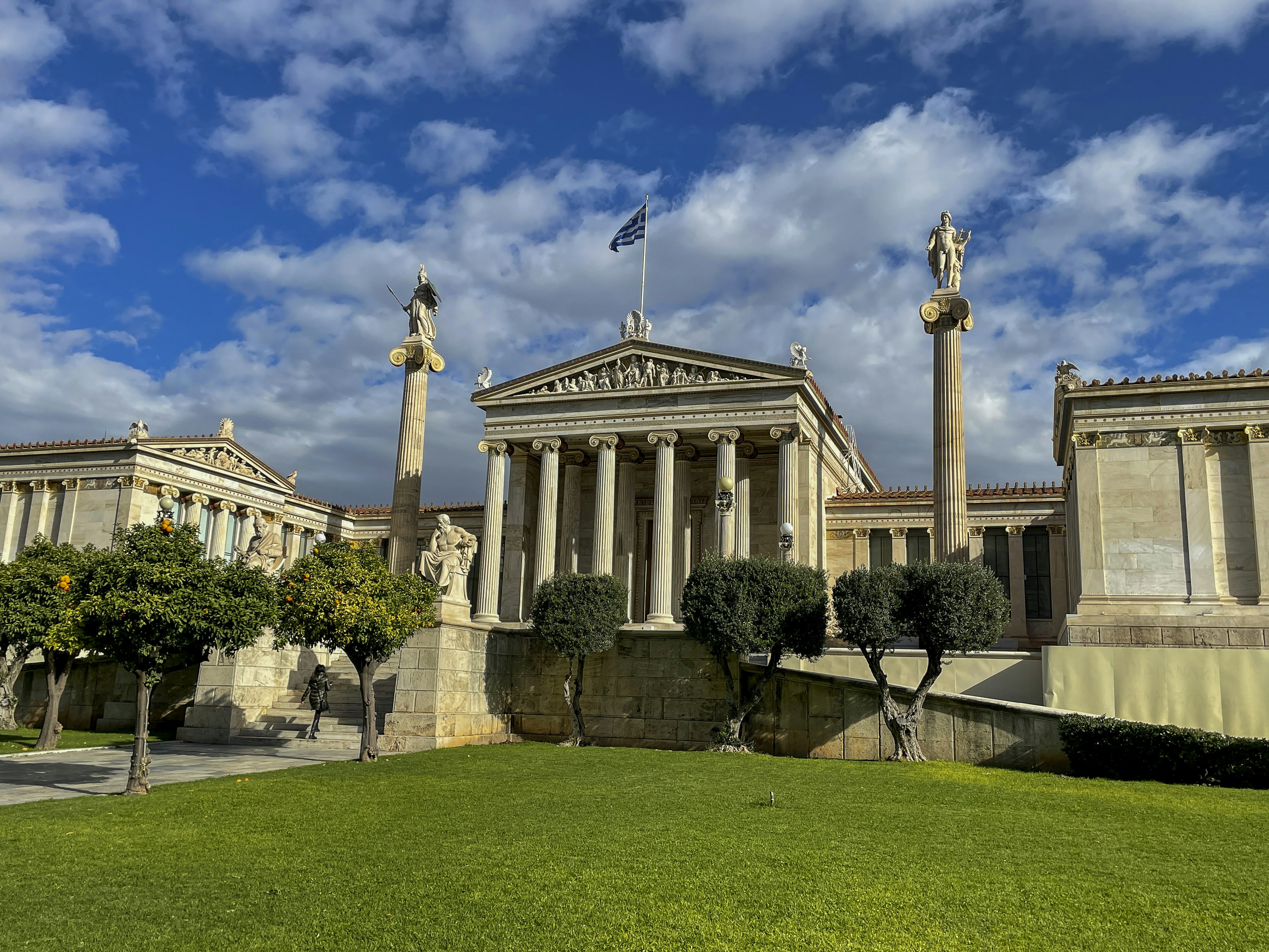 a building with columns and a flag on top of it, 
