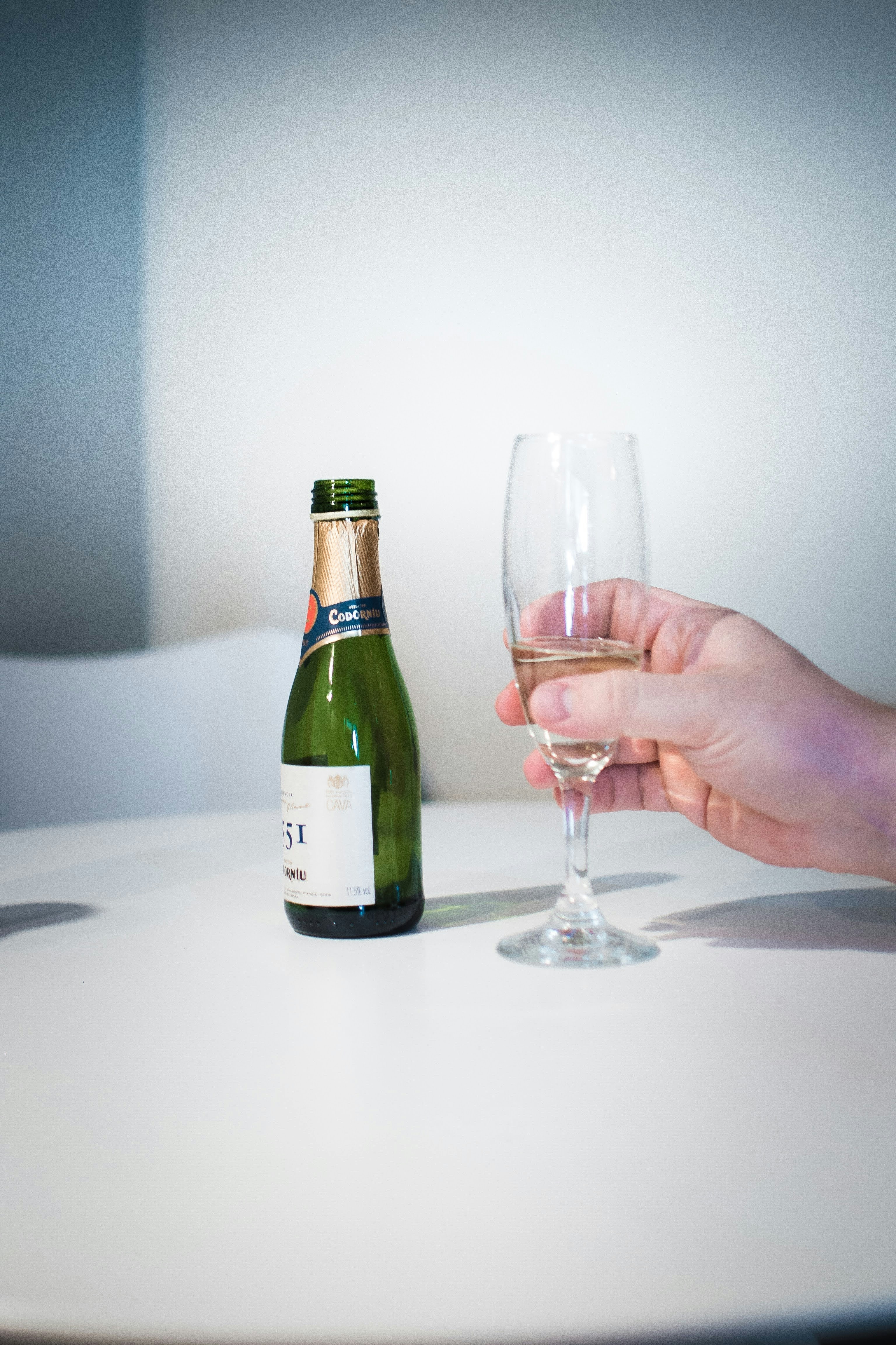 a person holding a wine glass next to a bottle of wine