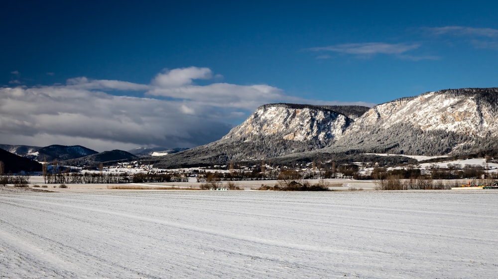 a snow covered field with mountains in the background