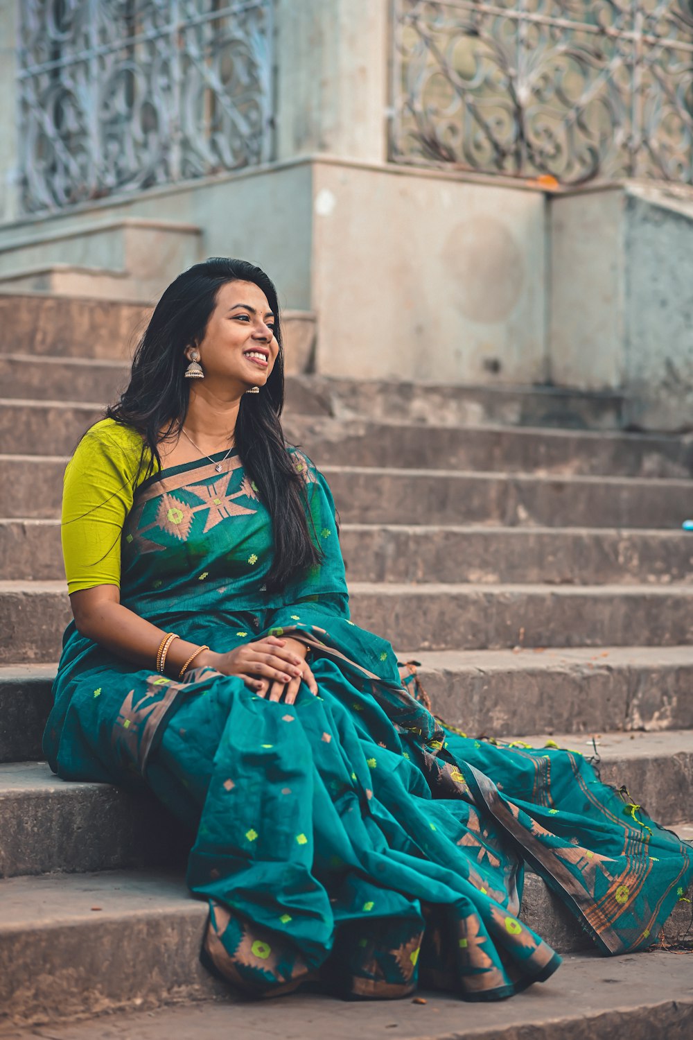 a woman in a green sari sitting on some steps