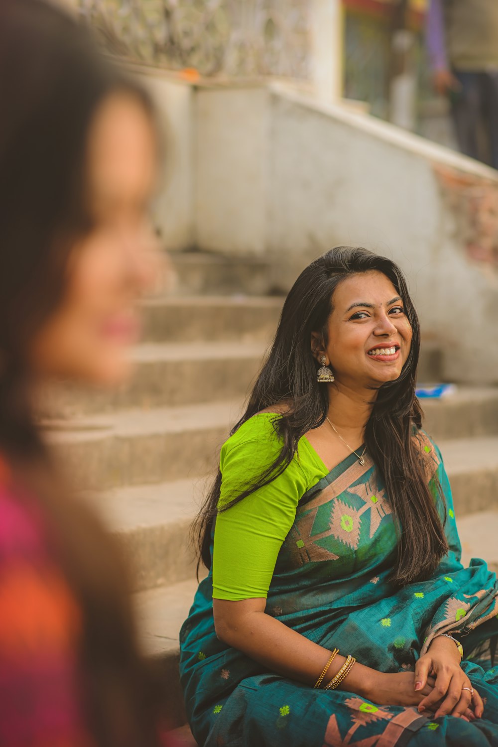 a woman in a green and blue sari sitting on steps