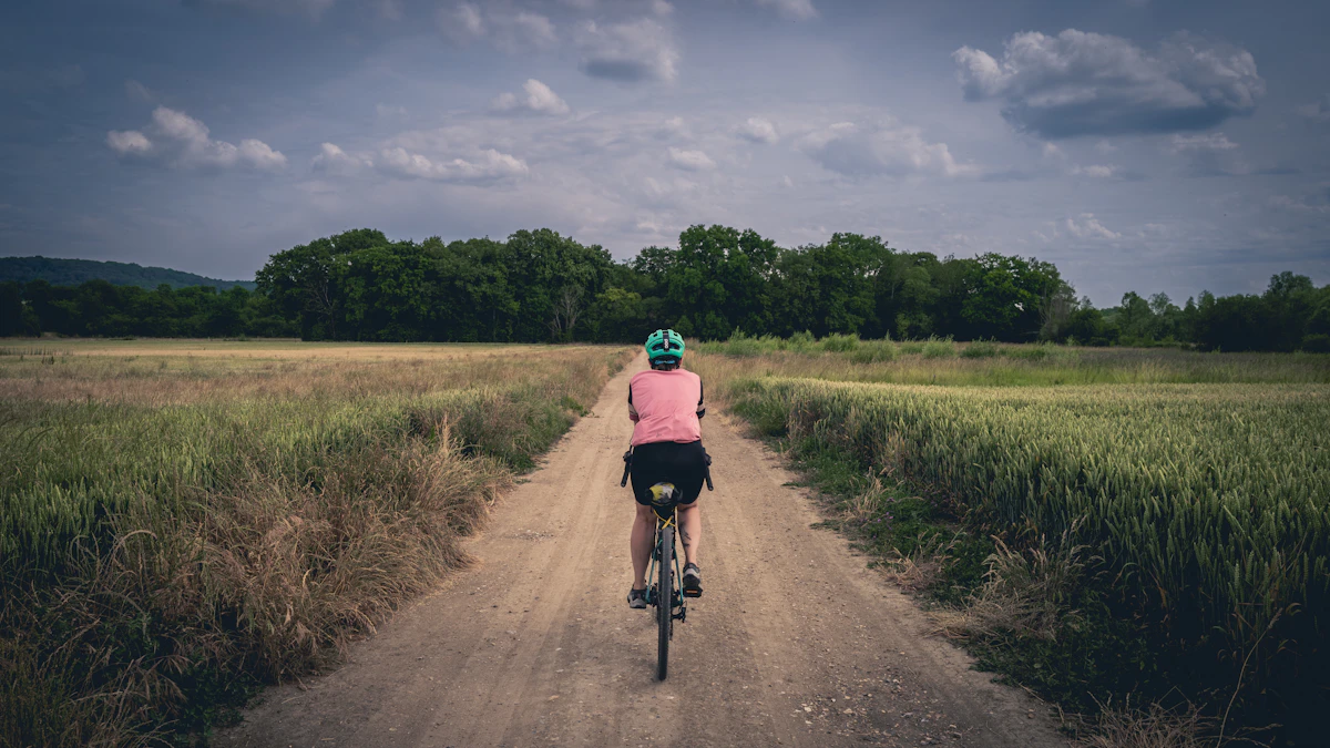 Ciclista su gravel bike percorre una strada sterrata tra campi verdi