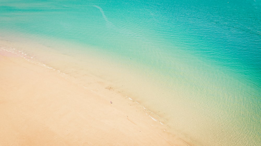 an aerial view of a beach with a boat in the water