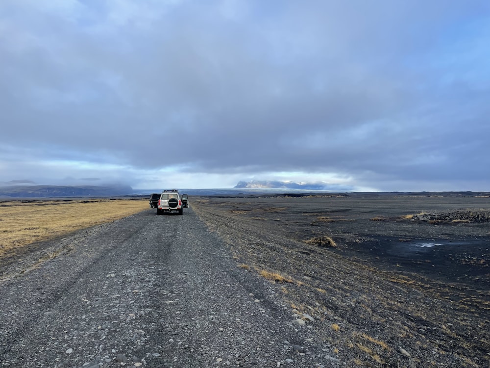 a truck driving down a dirt road in the middle of nowhere