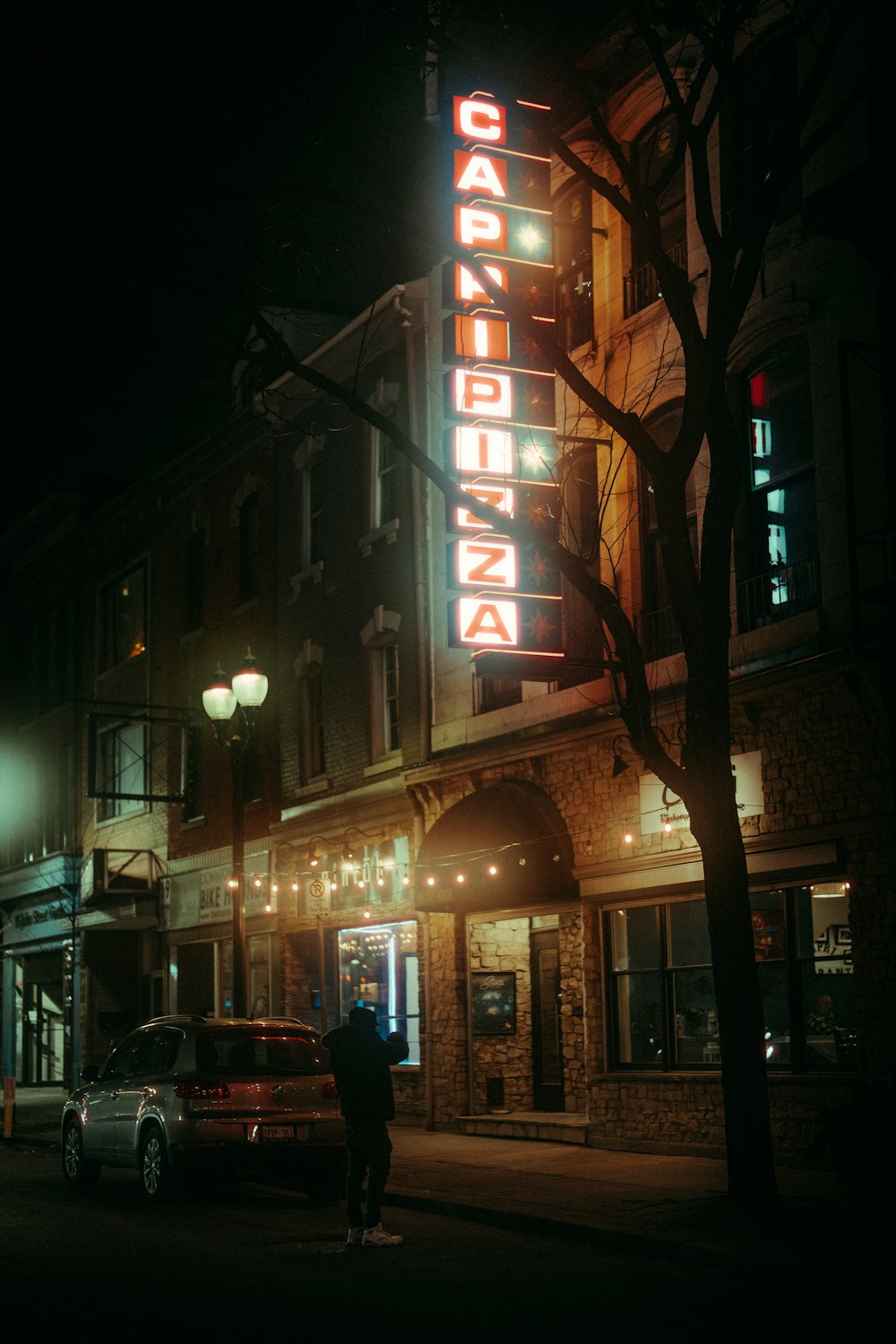 a person standing on the sidewalk in front of a building