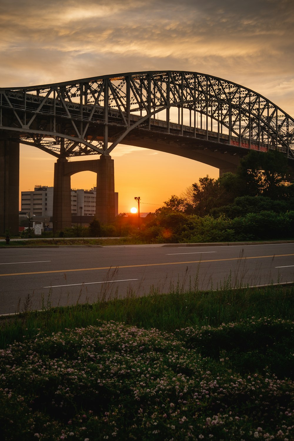 the sun is setting behind a bridge over a highway