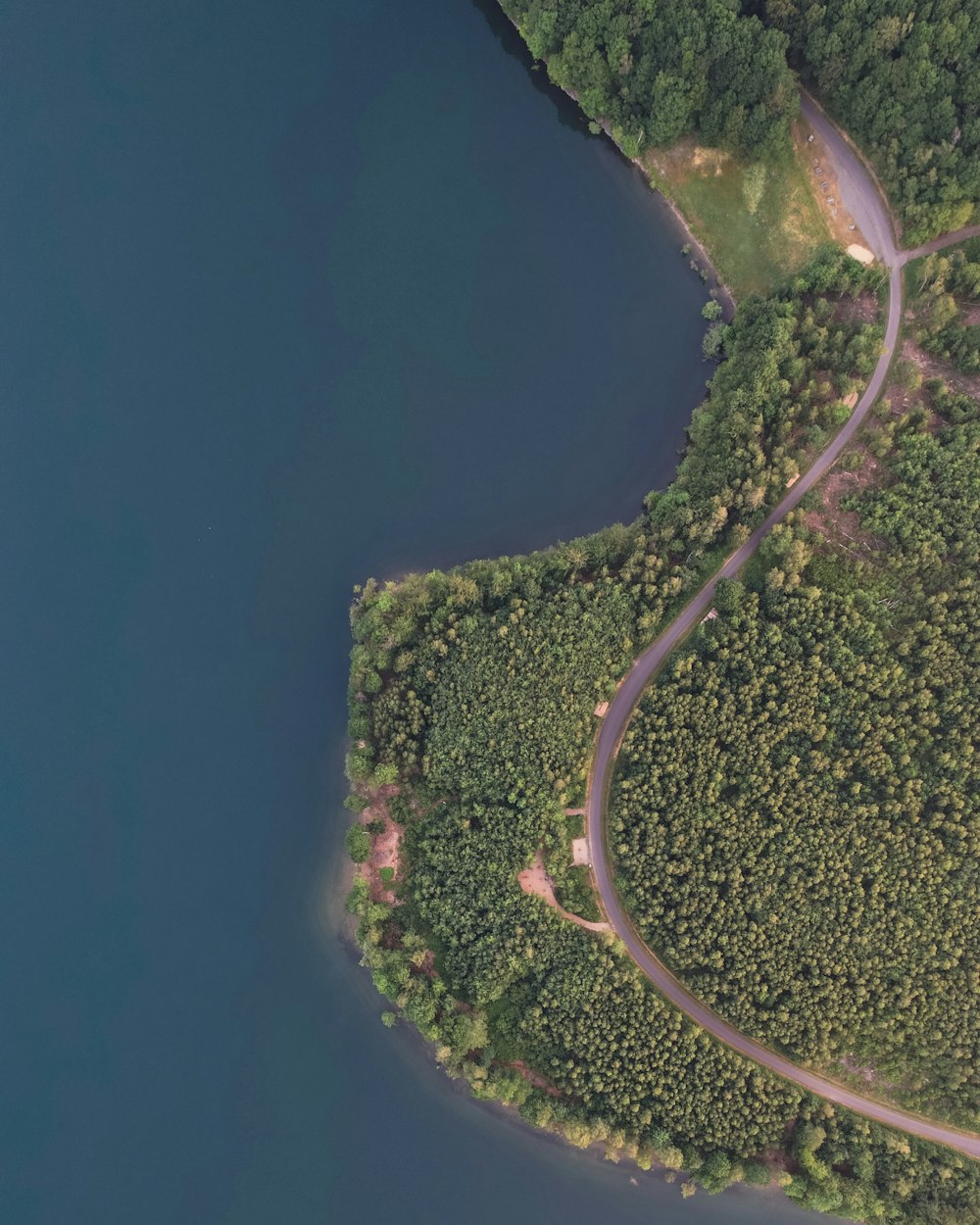 an aerial view of a winding road in the middle of a forest