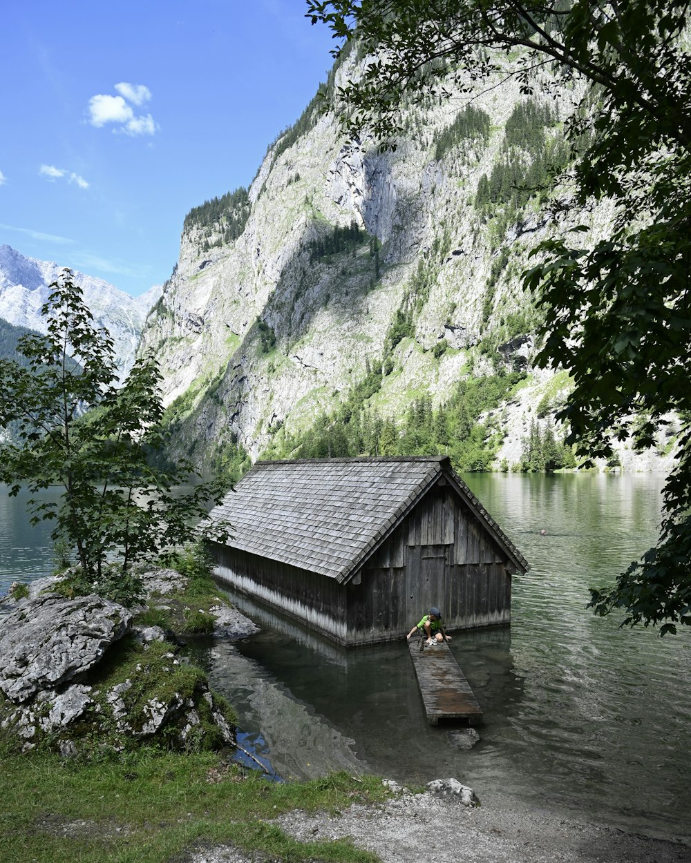 a boathouse in the middle of a lake with mountains in the background