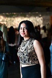 a woman in a black and gold dress standing in front of a group of people