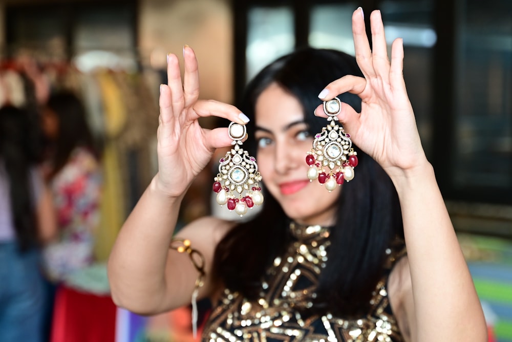 a woman holding up two pairs of earrings