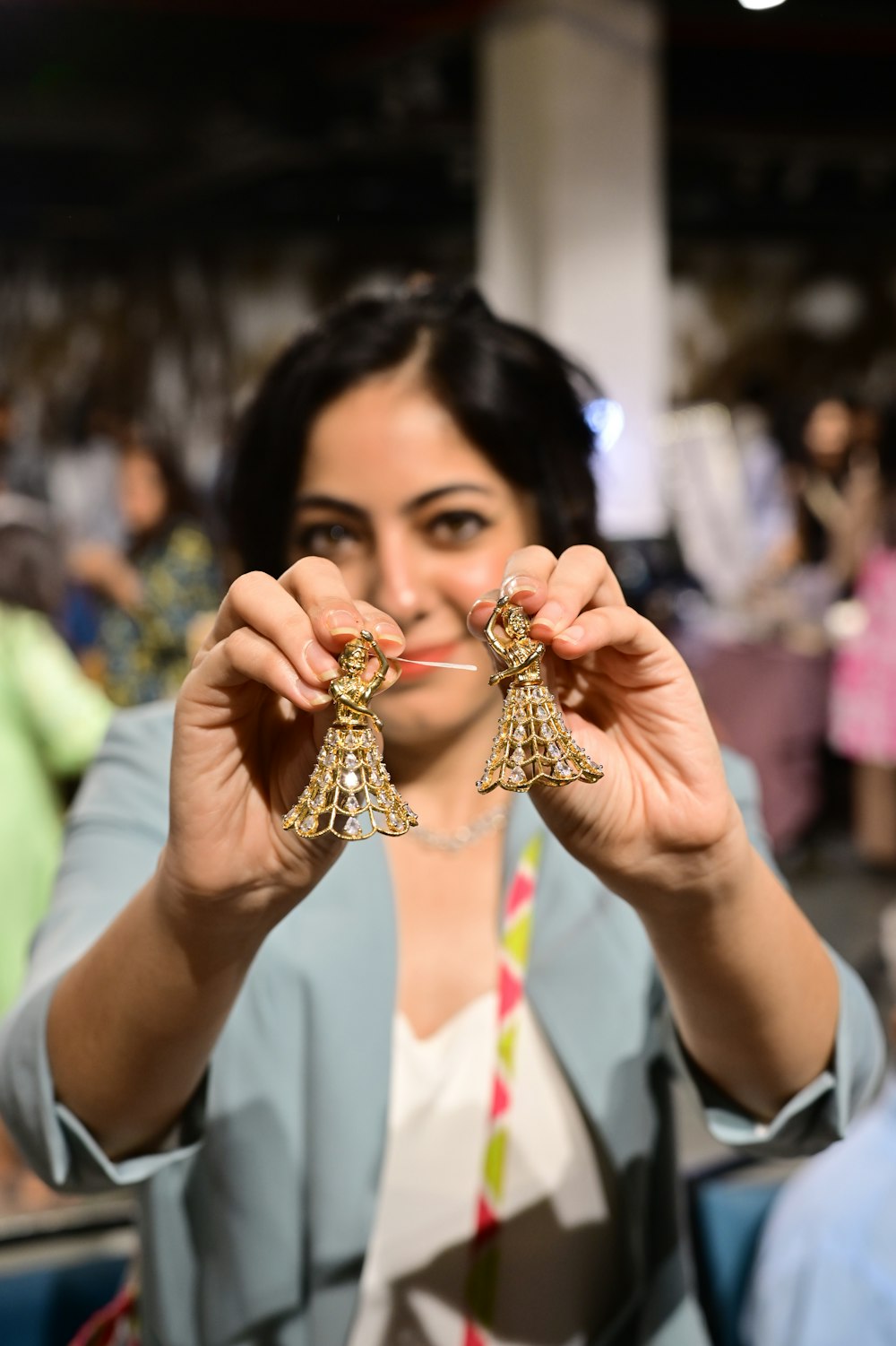 a woman holding a pair of earrings in front of her face