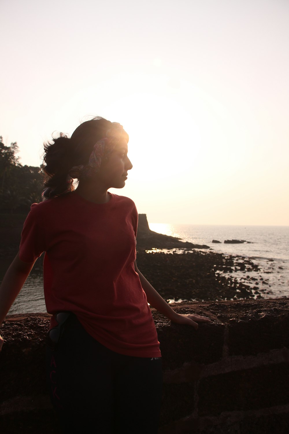 a woman in a red shirt standing next to the ocean