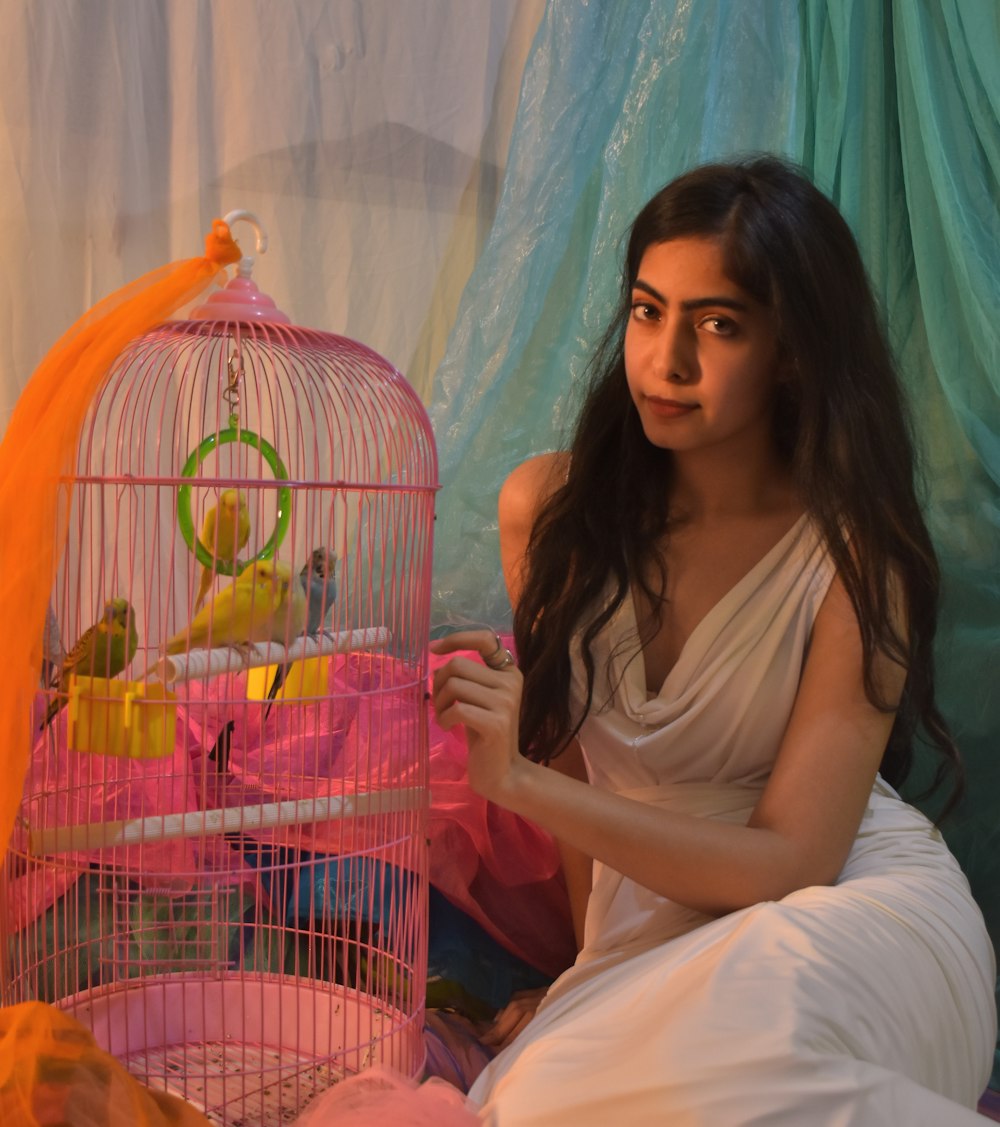 a woman sitting on a bed next to a bird cage